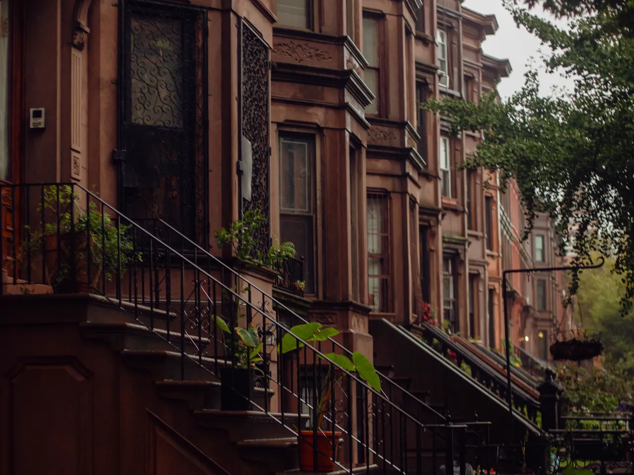 Calle residencial de Nueva York con casas de piedra rojiza y escalinatas de acceso.